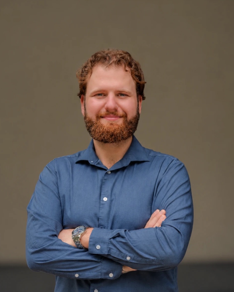 Russell Wagner, arms crossed, smiling, in a blue button-down shirt